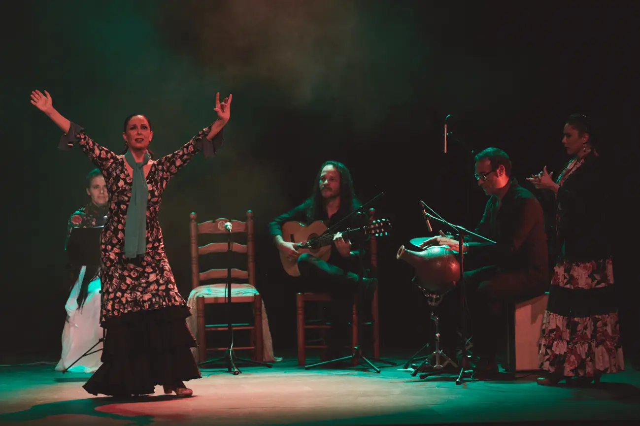 Bailaora flamenca con elenco de músicos en escena