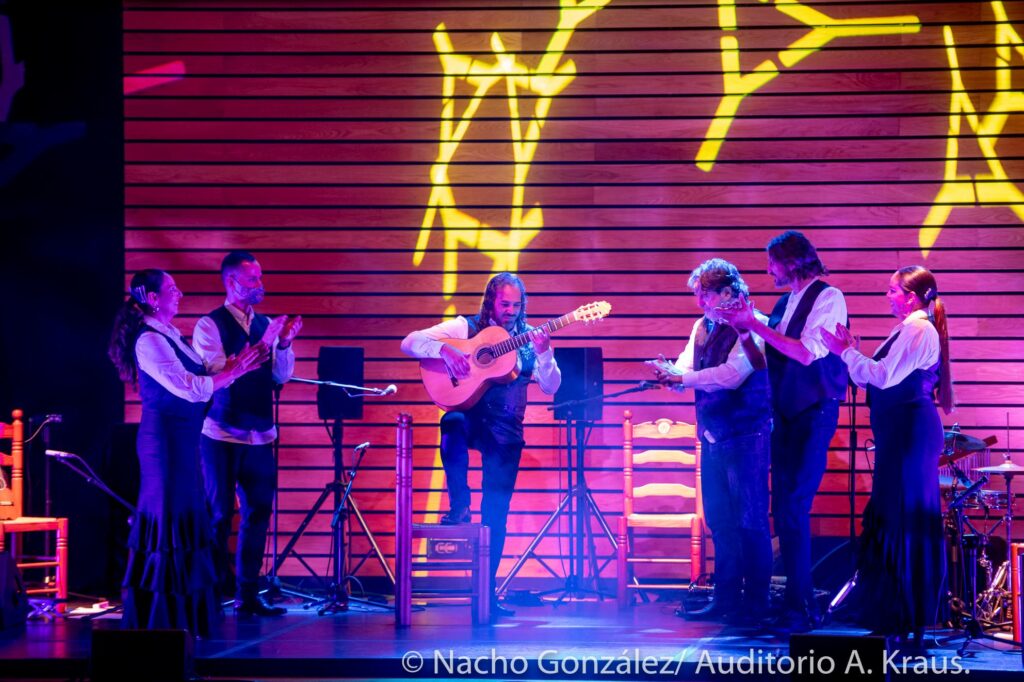 Espectáculo flamenco en escenario con varios artistas, iluminación profesional y letras decorativas
